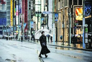 Man, wearing protective face mask, walks on Ginza boulevard during a snowfall in Tokyo