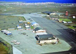 An aerial view of the ramp areas and facilities of the 57th Fighter Interceptor Squadron, with other facilities in the background.